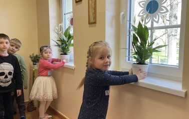 Dziewczynki ustawiają doniczki ze skrzydłokwiatami na parapetach